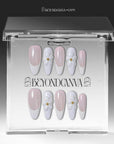 Press-on nails displayed in a clear BeyondCanva case with pale pink and white nails and 3D white flower accents.