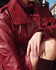 Seated lifestyle photo of Purple Dream lavender floral press-on nails styled with a red leather coat