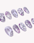 Angled flat lay of Purple Dream lavender floral nails with silver flower details and magenta rhinestones