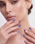 Rebel Cherry handmade press-on nails in a close-up portrait with blue accents, silver bows, and red cherry details
