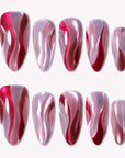 Rose Drift almond press-on nails with burgundy and pink cat eye wave designs arranged in a white background flat lay