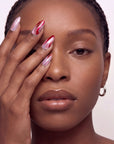 Rose Drift cat eye almond press-on nails shown in a face close-up with pink, burgundy and pearl wave details