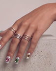 Hand model wearing silver holographic glitter press-on nails with large emerald-cut rhinestones in jewel tones.