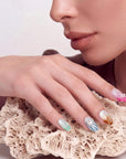 Hand model resting on coral-like stone while wearing multicolor pearl-textured press-on nails.
