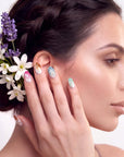 Hand model posing with multicolor pearl-textured press-on nails and flowers in the hair against a white background.