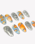 Angled flat lay of Solar Pulse orange, pale blue and silver chrome nails with hearts, swirls and bead details