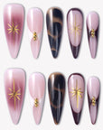 Starlit Mocha press-on nails with pink shimmer, black mocha cat-eye accents, gold starbursts, and bead details