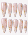 Starlit Veil press-on nails with sheer pink bases, white misty tips, gold starbursts, tiny gold studs, and pearl accents
