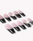 Angled flat lay of Timeless Serenity press-on nails with glossy nude bases, black French tips, subtle shimmer, and white flower accents