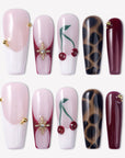 Wild Cherry press-on nails with pink sheer bases, burgundy accents, cherry art, leopard print, and gold embellishments