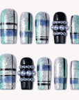 Flat lay of Winter Gridlight press-on nails with silver glitter, aqua blue, black, and pearl accents arranged in two rows