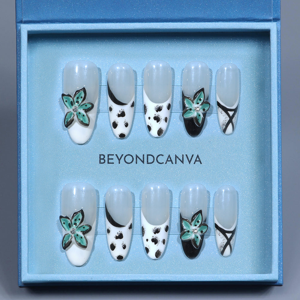 BEYONDCANVA press-on nails set with black and white patterns, teal floral accents, and crisscross designs, presented in a blue box and on a reflective surface.