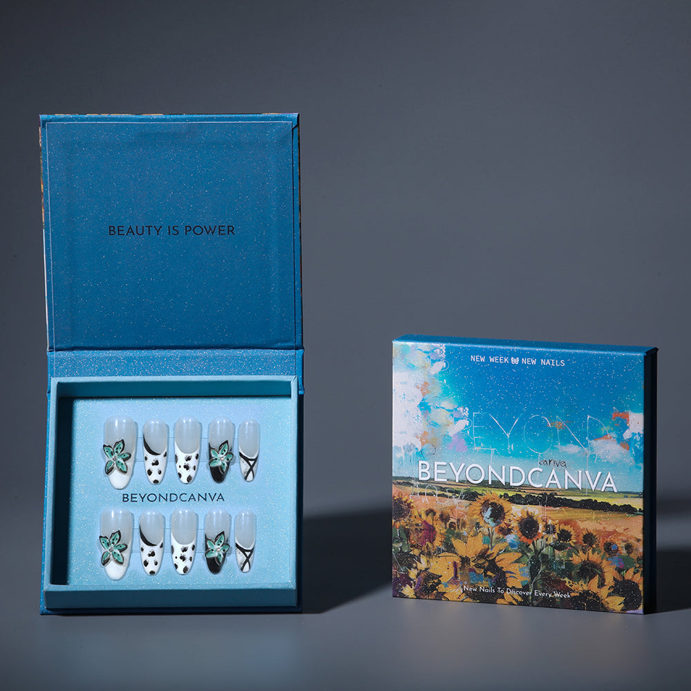 BEYONDCANVA press-on nails set with black and white patterns, teal floral accents, and crisscross designs, presented in a blue box and on a reflective surface.