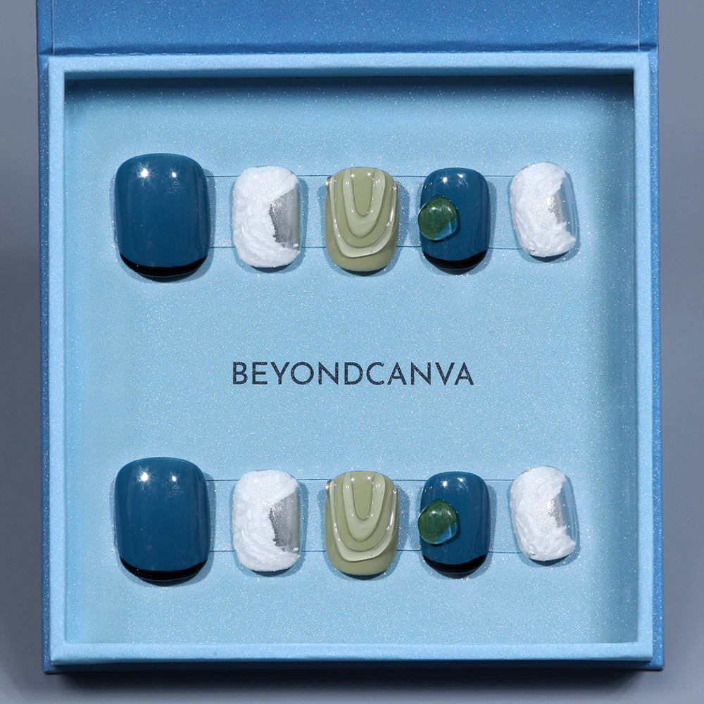 BEYONDCANVA press-on nails set featuring glossy blue, green, and white designs with textured and metallic details, presented in a blue box and on a reflective surface.