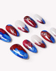 Set of press-on nails with blue, red, and white abstract swirl designs on a white background.
