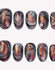 Set of handmade press-on nails with black, gray, and copper metallic fan patterns on a white flat lay.