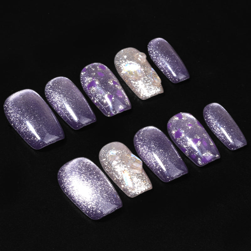 Flat lay of Amethyst Veil press-on nails with shimmering purple polish, silver glitter accents, translucent tips, and purple foil details