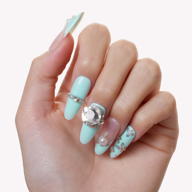 Hand model wearing Aqua Bijou press-on nails with mint blue and ivory tones, pearl accents, and a large crystal embellishment