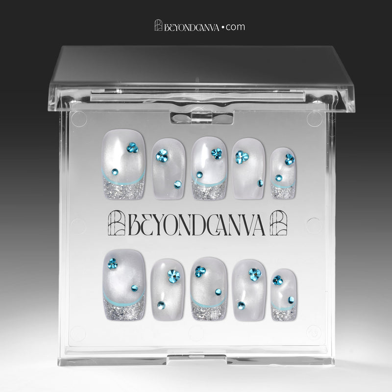 Clear BeyondCanva box displaying silver-white press-on nails with blue rhinestones and glitter tips.