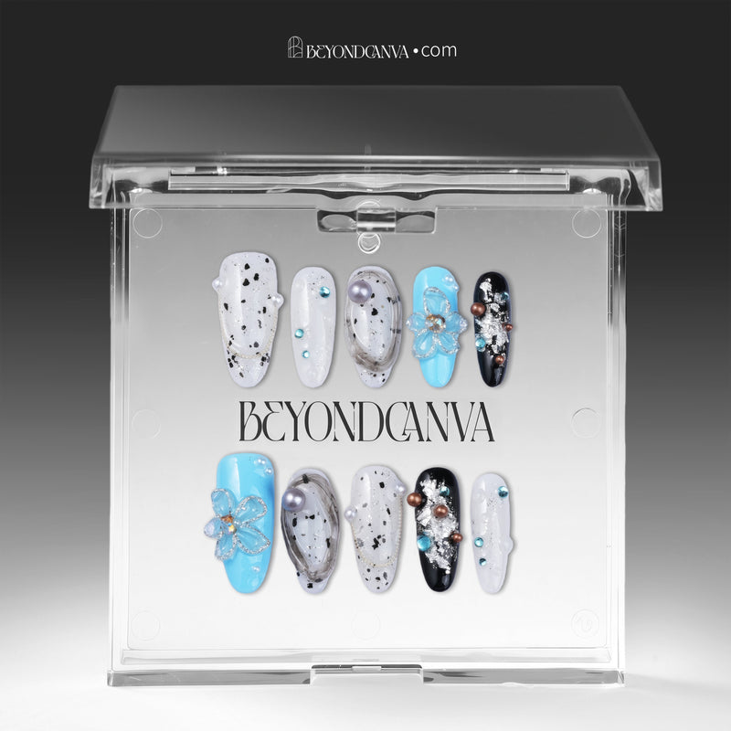 Artisian Orbit press-on nails displayed in a clear BeyondCanva case with white, black, and blue accents, pearl details, and gem embellishments
