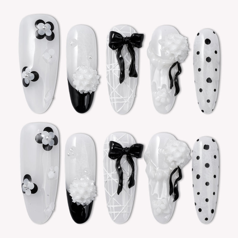 Flat lay of Atelier Hydrangeas press-on nail swatches with black and white floral accents, bows, and polka dots