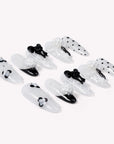 Flat lay of Atelier Hydrangeas press-on nails with black and white floral accents, bows, and polka dots arranged in two rows