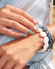 Aurelia turquoise, pearl and gold press-on nails styled outdoors with blue and white shell bracelets