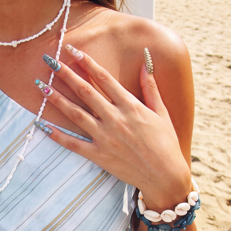 Outdoor model wearing Aurelia turquoise and gold sculpted press-on nails with pearl and jewel details