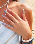 Outdoor model wearing Aurelia turquoise and gold sculpted press-on nails with pearl and jewel details