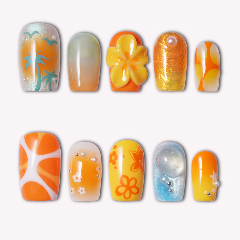 Orange and yellow press-on nails with palm tree, flower, glitter, and abstract designs on a white background.