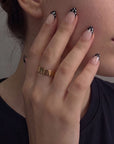 Close-up of a hand model wearing Bare Polka press-on nails in nude pink with black polka dot tips