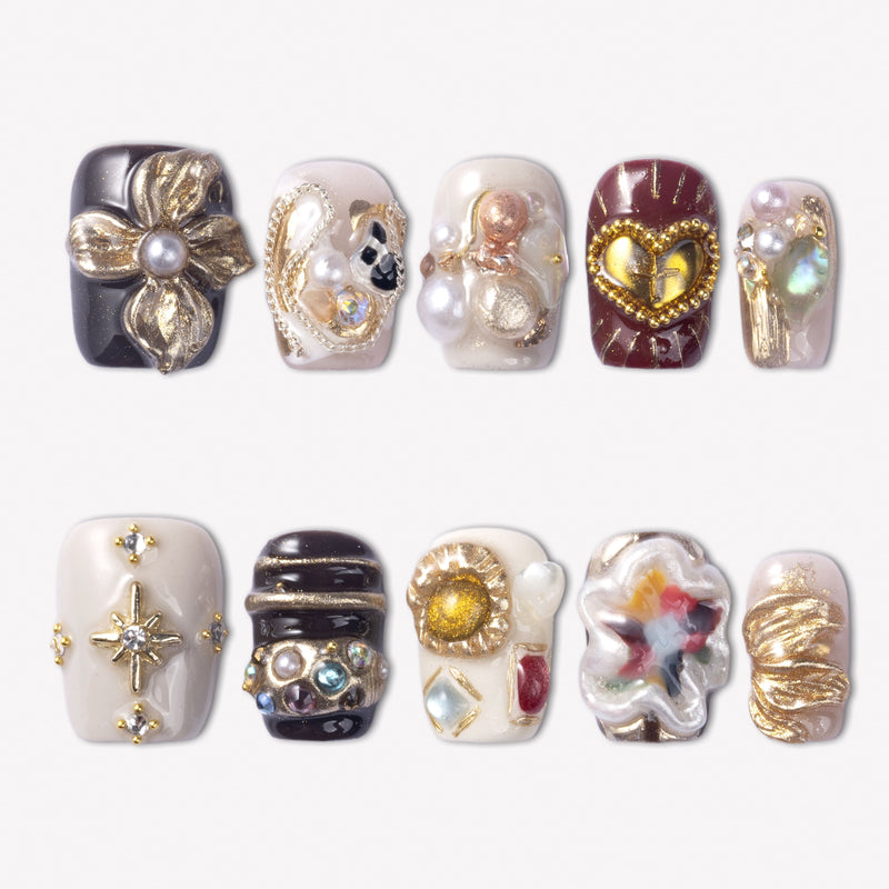 Baroque Treasures press-on nails with black, burgundy, and ivory designs, gold floral charms, pearls, rhinestones, and gemstone accents