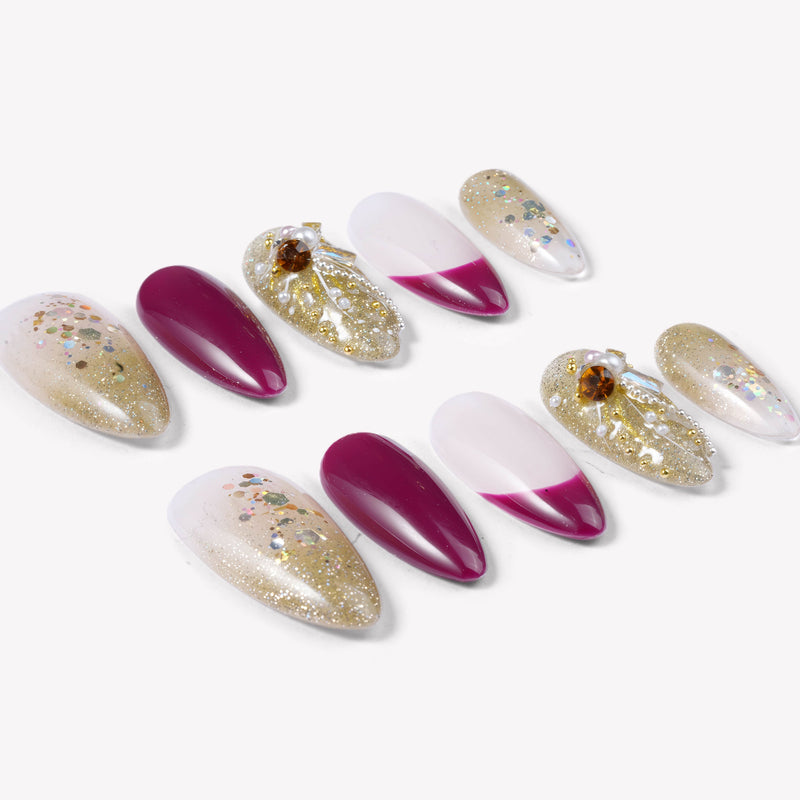 Flat lay of Berry Firelight press-on nails with burgundy, blush pink, gold glitter, and gemstone embellishments