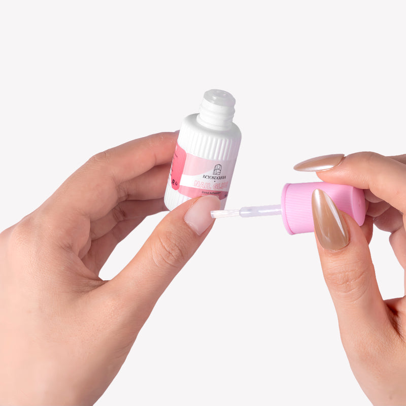 Close-up of Beyondcanva nail glue bottle with brush applicator held between manicured hands