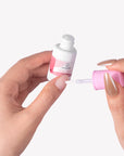 Close-up of Beyondcanva nail glue bottle with brush applicator held between manicured hands