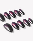 Flat lay of Bloody Tears press-on nails with glossy black bases, deep red cat eye shimmer, smoky blood-red gradient, and almond shapes