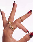 Hand model wearing Bloody Tears press-on nails with glossy black bases, deep red cat eye shimmer, smoky blood-red gradient, almond shapes, and gold rings