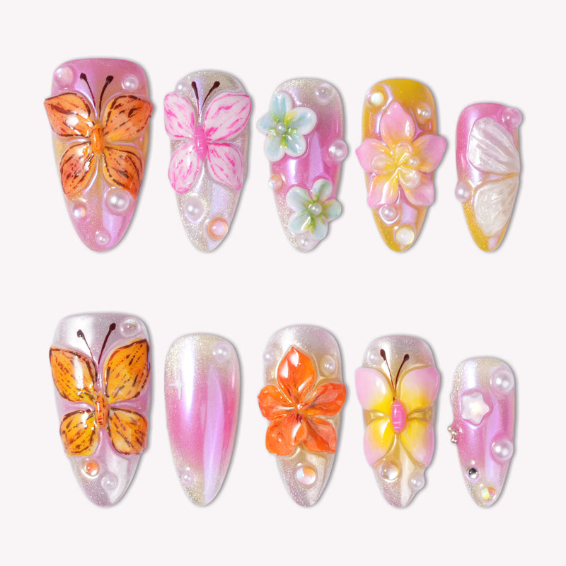 Bloom Pop pink press-on nails with raised orange butterflies, pastel flowers, pearls and a glossy ombre finish
