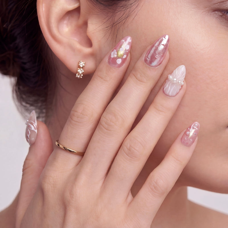 Model close-up wearing blush pink press-on nails with pearl accents and soft floral details.
