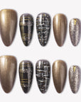 Flat lay of bronzed press-on nails with black plaid, gold stripe, and glitter accents