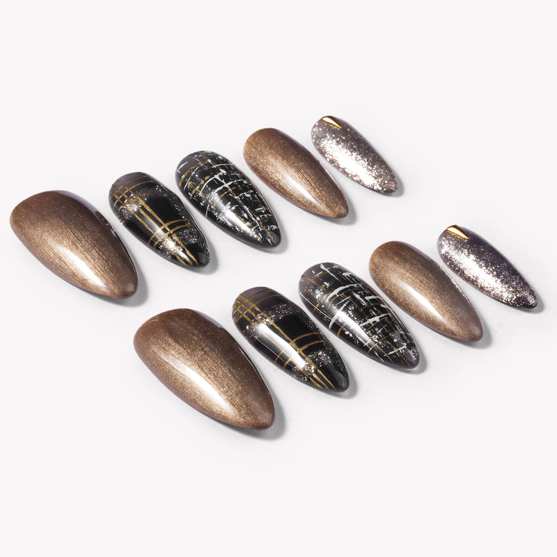 Flat lay of bronzed press-on nails with black plaid, gold stripe, and glitter accents arranged in sets
