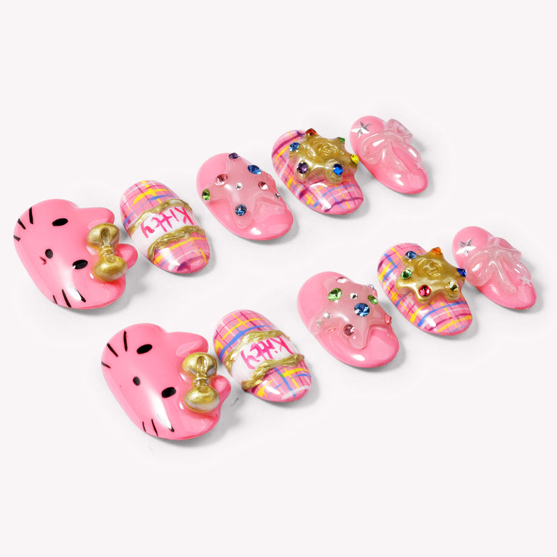 Bubblegum Pop Arcade handmade press-on nails arranged on a white background, showing pink plaid, gold accents, gems, and bow details.