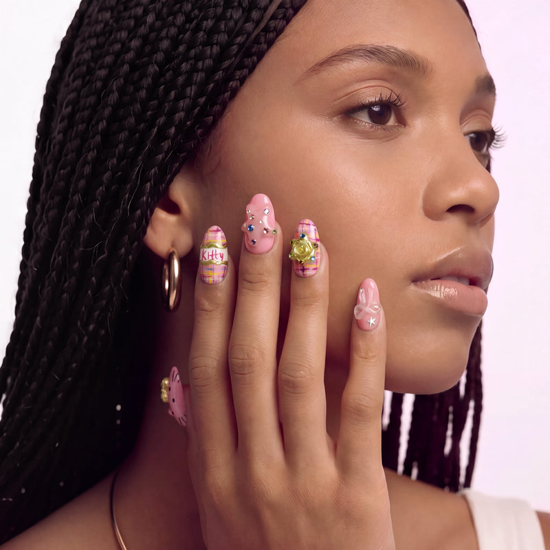Profile portrait of a hand model wearing Bubblegum Pop Arcade handmade press-on nails with pink plaid, gems, and gold accents.