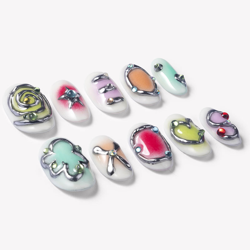 Flat lay of Candy Chrome press-on nails with silver chrome outlines, pastel heart star and bow designs, glossy candy colors, and rhinestone details