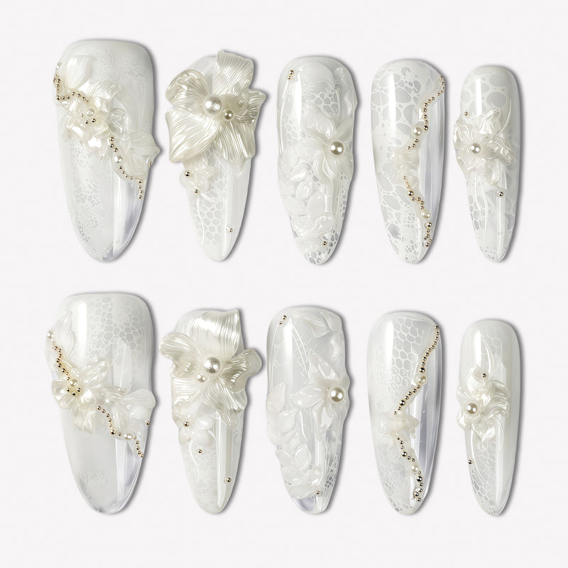 Celeste white floral press-on nails with pearl and gold bead accents arranged in a clean flat lay