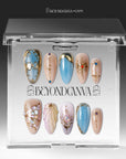 Press-on nails displayed inside a clear BeyondCanva case with blue, champagne, and gold celestial designs