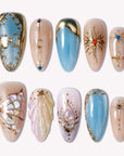 Celestial Gilded Fantasy handmade press-on nails with blue and nude bases, gold celestial accents, stars, and moons
