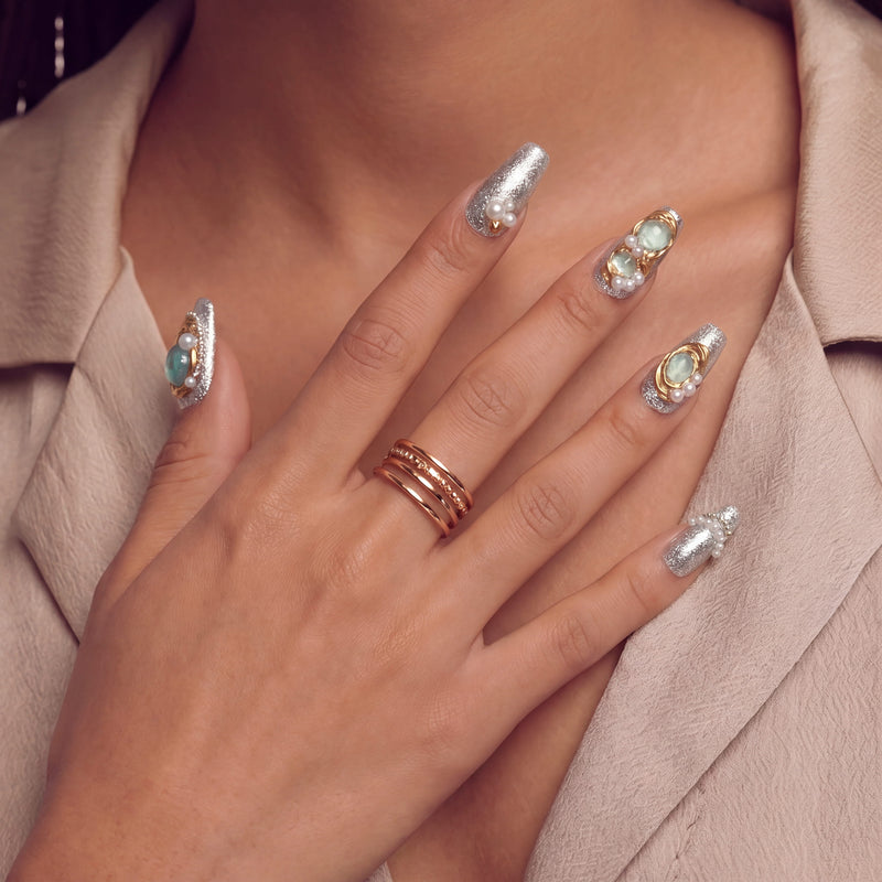 Hand model wearing Celestial Tide press-on nails with silver glitter, gold accents, pale blue stones, and pearl details