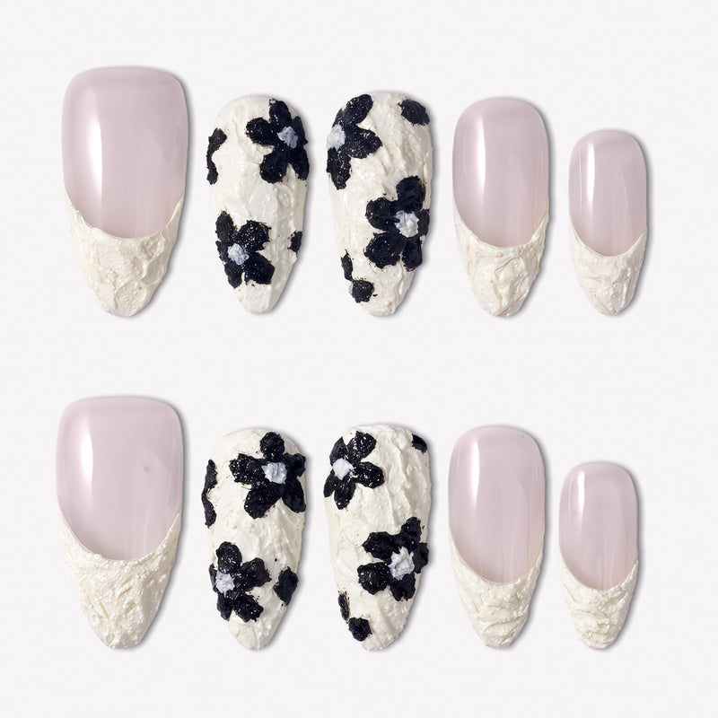 Chalk Floral press-on nails with nude pink bases, textured white French tips, and raised black flower designs