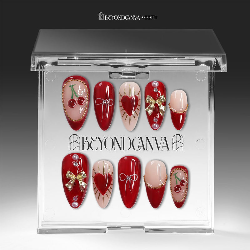 Cherry Devotion press-on nail set displayed in clear packaging with red, blush, and gold cherry, bow, and heart accents